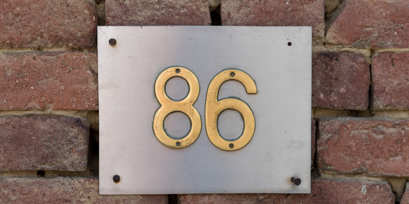 Silver modern metal house numb er plate with a gold 86 on it.