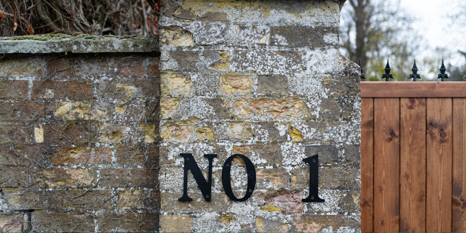 Extra large number 1 on a brink wall next to a house gate.