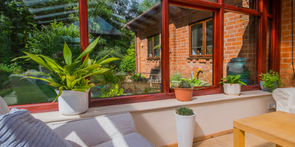 The inside of a conservatory with red wooden window frames.